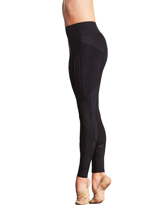 Person wearing black leggings in a minimal indoor setting