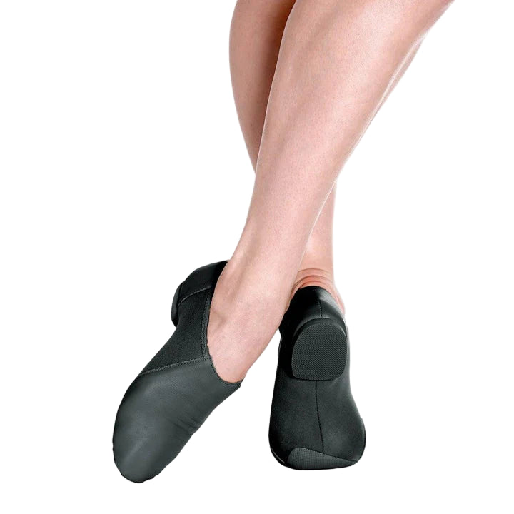 Black dance shoes worn by a person on a white background